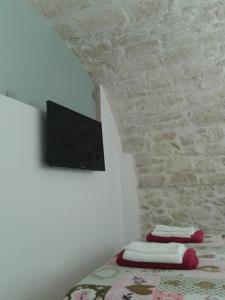 a bedroom with a bed with a tv on a stone wall at Lilla B&B in Molfetta