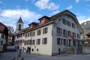 a large white building with a church in the background at Auberge Communale de St-Légier in Vevey