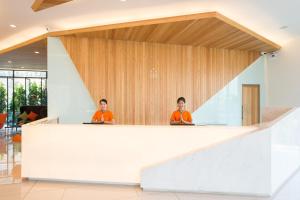dos personas sentadas en un mostrador en el vestíbulo en J Inspired Hotel Pattaya - SHA Extra Plus, en Pattaya central
