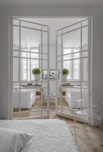 a bedroom with white furniture and a mirror at L'Hôtel Particulier in Arles