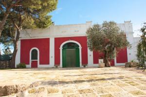 a red and white building with a green door at Masseria Sierro lo Greco in Laterza