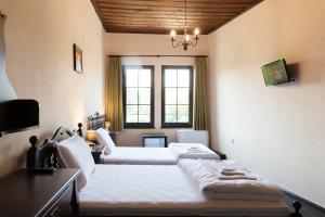 a bedroom with two beds and a desk and two windows at HiStory INN Unique Guest House in Veliko Tŭrnovo
