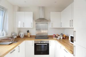 une cuisine avec des armoires blanches et un four à plaques de cuisson dans l'établissement Stones Throw, à Newquay