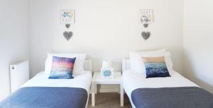 deux lits dans une chambre avec une table et deux oreillers dans l'établissement Stones Throw, à Newquay