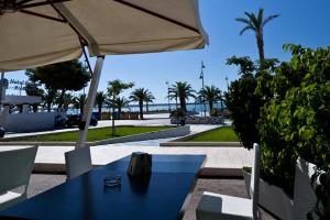 a blue table and chairs with an umbrella and palm trees at Divino Bed & Breackfast in Manfredonia