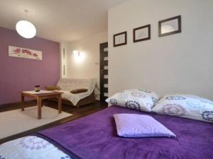 a bedroom with a purple bed and a table at Apartamenty Lawendowe in Krynica Zdrój