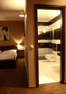 a bedroom with a bed and a bathroom with a toilet at Zala Aranya Panzió in Zalakaros