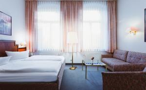 une chambre d'hôtel avec deux lits et un canapé dans l'établissement Hotel Kipping, à Dresde