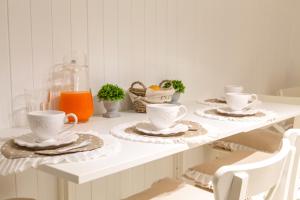 a white table with two cups and plates on it at il risveglio di alice in Fano