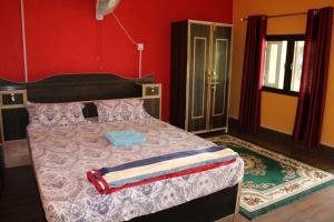1 dormitorio con cama y pared roja en Bardia Kingfisher Resort, en Dhakela