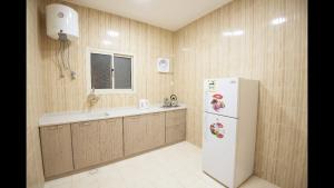 a kitchen with a white refrigerator and a sink at Janan Al Nakheel Serviced Apartments in Al Muzāḩimīyah