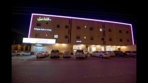 a large building with cars parked in a parking lot at Janan Al Nakheel Serviced Apartments in Al Muzāḩimīyah