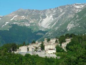 a village on a hill with a mountain at villino in montagna in Montemonaco