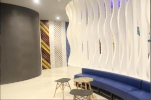 a room with a blue couch and two stools at Passgo Digital Airport Terminal 3 Soekarno Hatta in Tangerang
