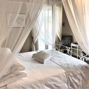 a bedroom with a white bed with curtains and a window at B&B Baronia Luxury Rooms in Castel Baronia