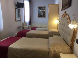 a hotel room with three beds and a mirror at Alloggi SS Giovanni e Paolo in Venice
