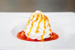 a dessert with whipped cream and sauce on a plate at Domaine Utah Beach - Le Grand Hard in Sainte-Marie-du-Mont