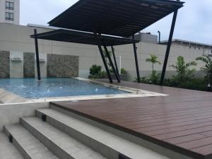 a swimming pool with a wooden deck and a black umbrella at Spacious 1 Bedroom Unit at Centrio Tower in Cagayan de Oro +1 photo
