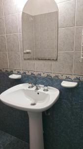 y baño con lavabo blanco y espejo. en Departamentos Dani en Villa Carlos Paz