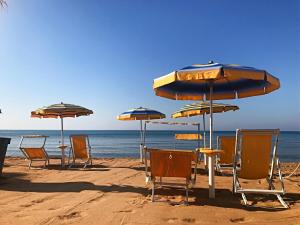 een groep stoelen en parasols op een strand bij Triscinamare Hotel Residence in Triscina