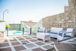 un patio con sillas blancas y una piscina en Apartamentos Turísticos La Casa Vieja, en Sabiote