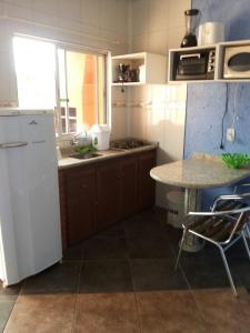 a kitchen with a white refrigerator and a table at Pousada da Guarda in Guarda do Embaú