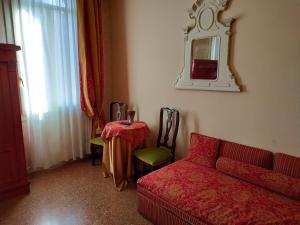 Alloggi Acquavita - checkin at "Alloggi SS Giovanni e Paolo" في البندقية: غرفة معيشة مع أريكة حمراء وطاولة