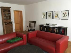 a living room with two red couches and a book shelf at Storchenblick in Straupitz