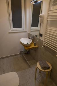 a bathroom with a sink and a mirror and a stool at UP&B Rooms Catania in Mascalucia