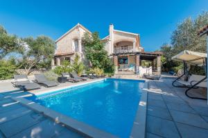 a swimming pool in front of a house at Poolside Stone Residences - Marina Bok in Novalja