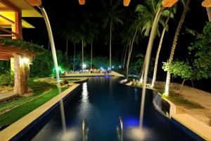a pool at a resort at night with palm trees at Punta Bulata White Beach Resort & Spa in Sipalay