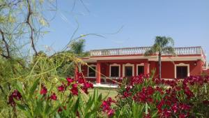una casa rossa con dei fiori davanti di B&b Elda Salento a Tuglie