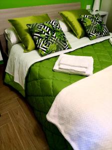 duże łóżko z zieloną i białą pościelą i poduszkami w obiekcie Holiday In Home | Le Ciminiere w Katanii