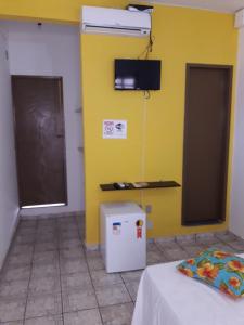 a room with a yellow wall and a white refrigerator at Pousada Pelourinho in Mucuri
