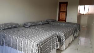 three beds are lined up in a room at Pousada Aerogrill in Juazeiro do Norte