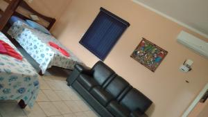 um quarto com uma cama e um sofá de couro em Pousada Pesque Park em Boraceia