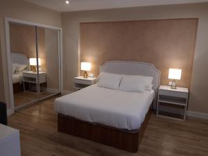 sypialnia z białym łóżkiem i 2 lampkami na stołach w obiekcie H.Albar Mieres w mieście Mieres
