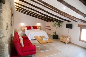 a bedroom with a bed and a red chair at Apartamentos Turísticos La Casa Vieja in Sabiote