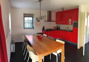 スコールルにあるVakantiehuis Zeeduinenbosのキッチン(木製テーブル、赤いキャビネット付)