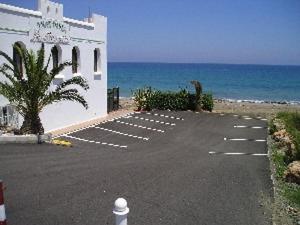 モハカルにあるHotel Playaの白い建物の海辺の駐車場