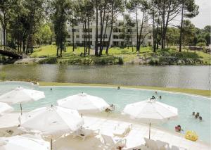 een zwembad met witte parasols en een waterlichaam bij Departamento en Greenpark in Punta del Este