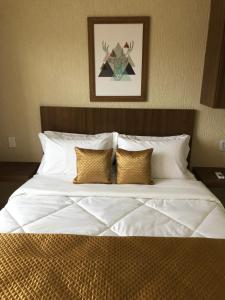 um quarto com uma cama grande com lençóis brancos e almofadas em Areias de Tucuns Lofts e Apartamentos em Búzios