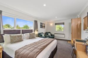 a hotel room with a large bed and a desk at Colombo In The City in Christchurch
