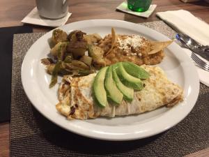 a white plate of food with avocado and potatoes at Hotel Ht Ole in Tijuana