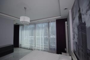 ワルシャワにあるApartamenty Triston Parkのシャンデリア付きの大きな窓が備わる客室です。