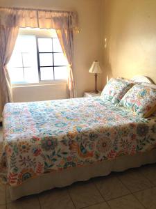a bedroom with a bed with a flowered blanket and a window at Ocean Edge Villa in Boscobel