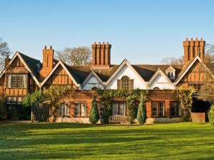 a large house with a green lawn in front of it at Macdonald Alveston Manor Hotel & Spa in Stratford-upon-Avon