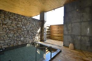 a room with a stone wall and a glass at Hamamura Onsen Totoya in Tottori