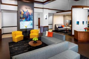 uma sala de estar com um sofá azul e cadeiras amarelas em Hyatt Place Topeka em Topeka