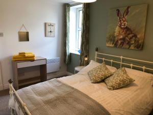 a bedroom with a bed with a painting of a rabbit on the wall at The Grey Cottage in Blackford